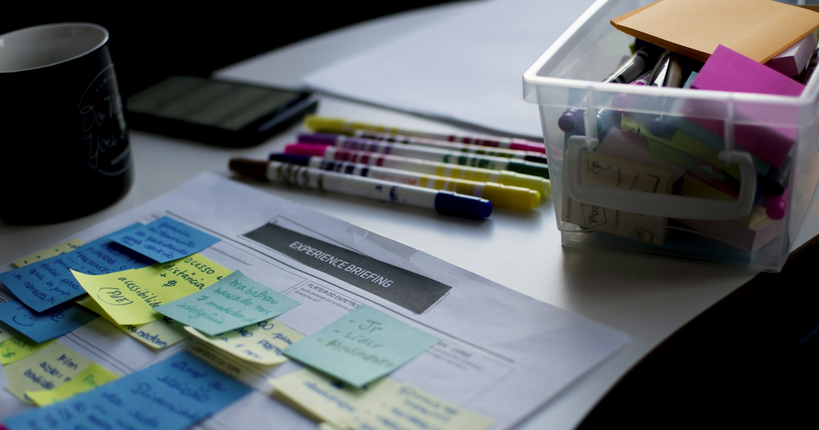 Notas adesivas coloridas e canetas sobre uma mesa de estudo